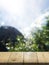 Wooden table, perspective view. Behind a blurry wooden table, a garden or a forest and the sun shines at the dawn of the day.