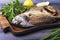 On a wooden table plate with two roasted carp fish dorado
