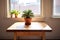 a wooden table with a single potted succulent in bright, natural light