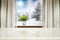 A wooden table and snowy winter background outside the window and space for products and decorations.