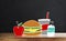 Wooden table top with drawing breakfast, Hamburger, apple, juice and milk, on black wall backgrounds