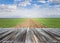 Wooden table top with fresh green agricultural field and blue sky in summer. Space for present a product