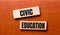 On a wooden table are two wooden blocks with the text question CIVIC EDUCATION