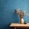 Wooden table with vase with bouquet of dried field flowers near empty, blank blue wall. Home interior with copy space