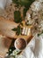 Wooden tabletop in bed with cup of cappuccino, open book, bubble cube candle and bunch of white lilac.