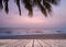 Wooden terrace over tropical island beach with coconut palm at sunset or sunrise time