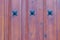 Wooden texture background. Closeup of a detail from a wooden red brown entrance door with three metal stars on the wooden planks.