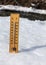 Wooden thermometer standing in ice on partially frozen river, sun shining, showing +3 degrees. Image to illustrate winter leaving