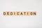 Wooden tile spelling the word dedication isolated on a white background