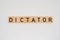 Wooden tile spelling the word dictator isolated on a white background