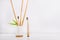 Wooden toothbrushes, one standing with fresh bamboo canes and leaves in white holder with bamboo basis and another on