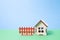 wooden toy house from the constructor for children, brown fence on a blue background, green background