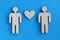 Wooden toy men and heart lying on blue background