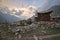 Wooden traditional house with rock wall during sunset at mountain top.