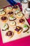 Wooden tray of appetizers on pallet coffee table at banquet with beetroot, citron, green herbs and hummus.