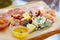 Wooden tray with assorted meats and cheeses with sauces.