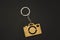 Wooden trinket in the form of a camera on a black background. keychain