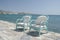 wooden turquoise chairs with soft cushions stand on the promenade next to the sea