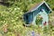 Wooden turquoise summerhouse in beautiful summer garden with lots of blooming flowers