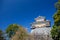 wooden turret or yagura on stone wall of Kumamoto castle in Japan with green tree