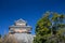 wooden turret or yagura on stone wall of Kumamoto castle in Japan with green tree