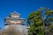 wooden turret or yagura on stone wall of Kumamoto castle in Japan with green tree