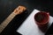 Wooden ukelele on a black desk next to a mug with a hot drink and a notebook for inspiration concept on a music production studio.