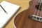 Wooden ukulele and notebook on wooden background