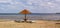 Wooden umbrella and sunbeds or beach lounger on the empty beach by the lake