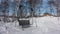 Wooden unpainted swing-bench stand among the snowdrifts