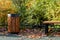 A wooden urn and a comfortable empty park bench. A cozy place to relax for a walk.