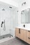 A wooden vanity with a large, marble tile shower.