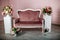 Wooden velvet vintage bench next to white nightstands and flower bouquets