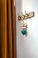 Wooden vintage style hanger with decorative cyan heart and orange curtain. Hooks on a wall at an entrance to home