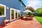 Wooden walkout deck in the backyard garden of blue siding house.