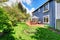 Wooden walkout deck in the backyard garden of blue siding house.