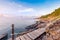 Wooden walkway bridge seashore with mountain landscape in sunrise