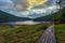 A wooden walkway leads to the wooden buildings in a reserved place amid beautiful nature