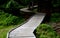 Wooden walkway in a nature reserve in a spruce forest in the mountains over a waterlogged peat bog, gray solid wood across 1m wide