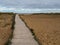 Wooden walkway to beach and horizon with beach huts and dunes