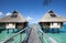 Wooden walkways over the water of the blue tropical sea to authentic traditional Polynesian thatched roof houses