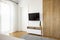 Wooden wardrobe next to television on white wall in hotel bedroom interior with door. Real photo