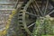 Wooden water paddle wheel and mossy stones on the side of a old