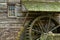 Wooden water paddle wheel and mossy stones on the side of a old