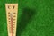 Wooden weather thermometer measurement on a green grass during a hot day