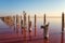 Wooden weathered logs for salt extraction in the pink water of extremely salty lake, amazing nature landscape with blue sky