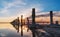 Wooden weathered posts in the form of a gate for salt extraction in pink water of salt lake with blue sky in Ukraine