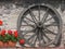 Wooden wheel with wooden spokes next to red flowers