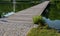 Wooden wide pedestrian bridge over the river pond lake, without railings design of gray oak wood connects to the stone path of nat