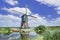 Wooden windmill near a canal on a summer day with blue sky and clouds, Netherlands.